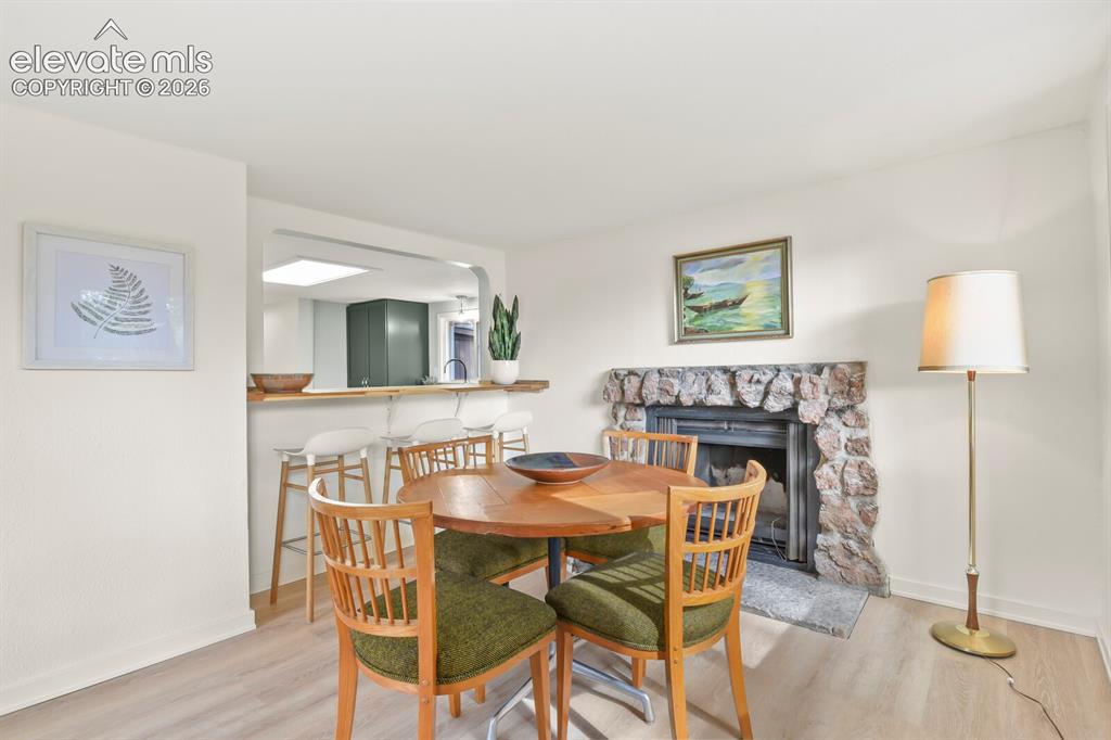 Image 19 of 39: Dining area with original wood burning fireplace and breakfast bar to the k