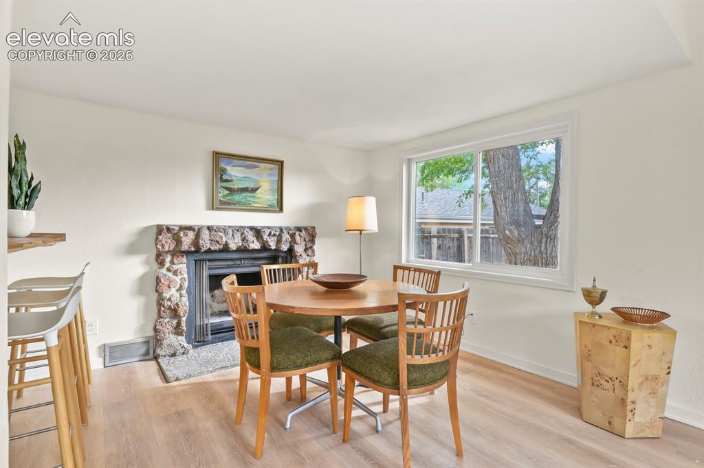 Image 4 of 39: Dining area with original wood burning fireplace and breakfast bar to the k