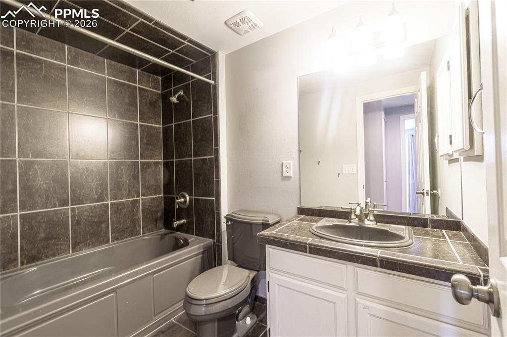 Image 13 of 25: Bathroom with toilet, vanity, shower / washtub combination, and visible ven