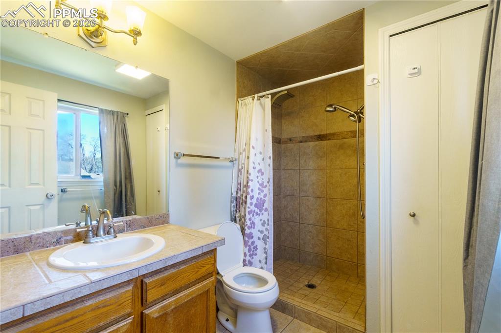 Image 14 of 25: Primary Bathroom featuring tiled shower, vanity, and toilet
