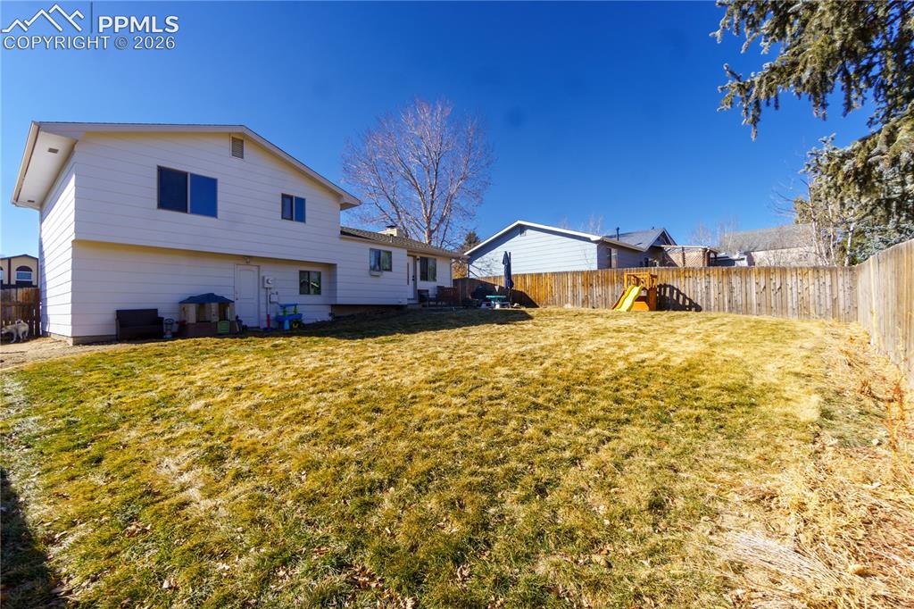 Image 23 of 25: Back of property with a fenced backyard and a lawn