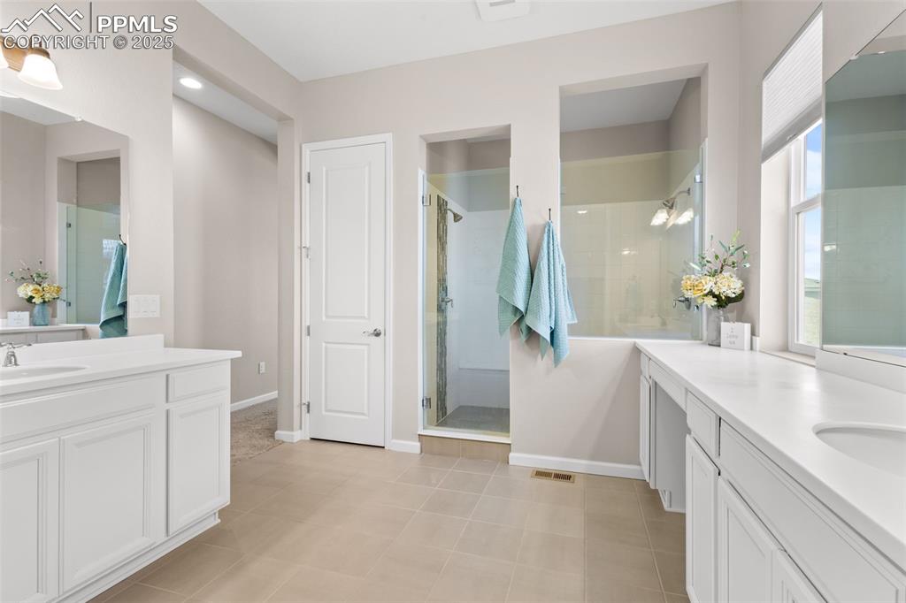 Image 17 of 47: Full bathroom with two vanities, a stall shower, and tile patterned floors