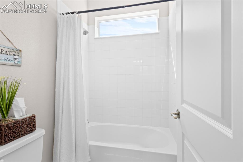 Image 20 of 47: Bathroom featuring toilet and shower / bathtub combination with curtain
