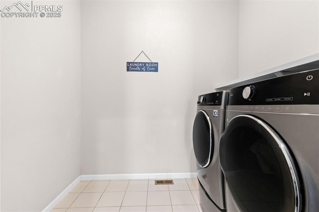 Image 24 of 47: Laundry room with washing machine and clothes dryer and light tile patterne