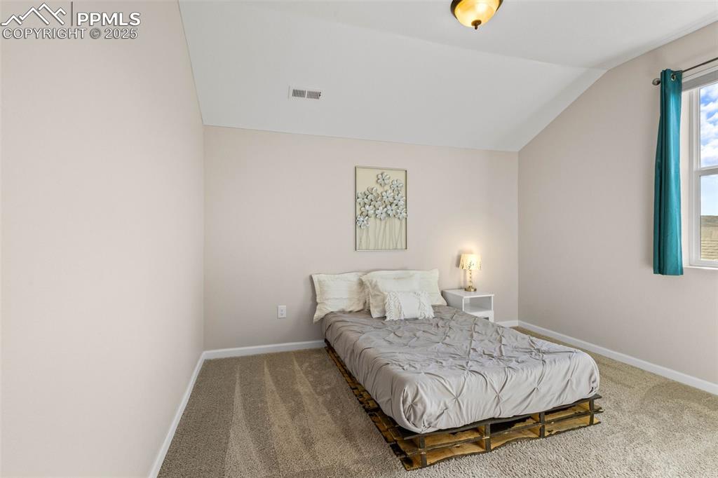 Image 28 of 47: Carpeted bedroom featuring lofted ceiling and baseboards