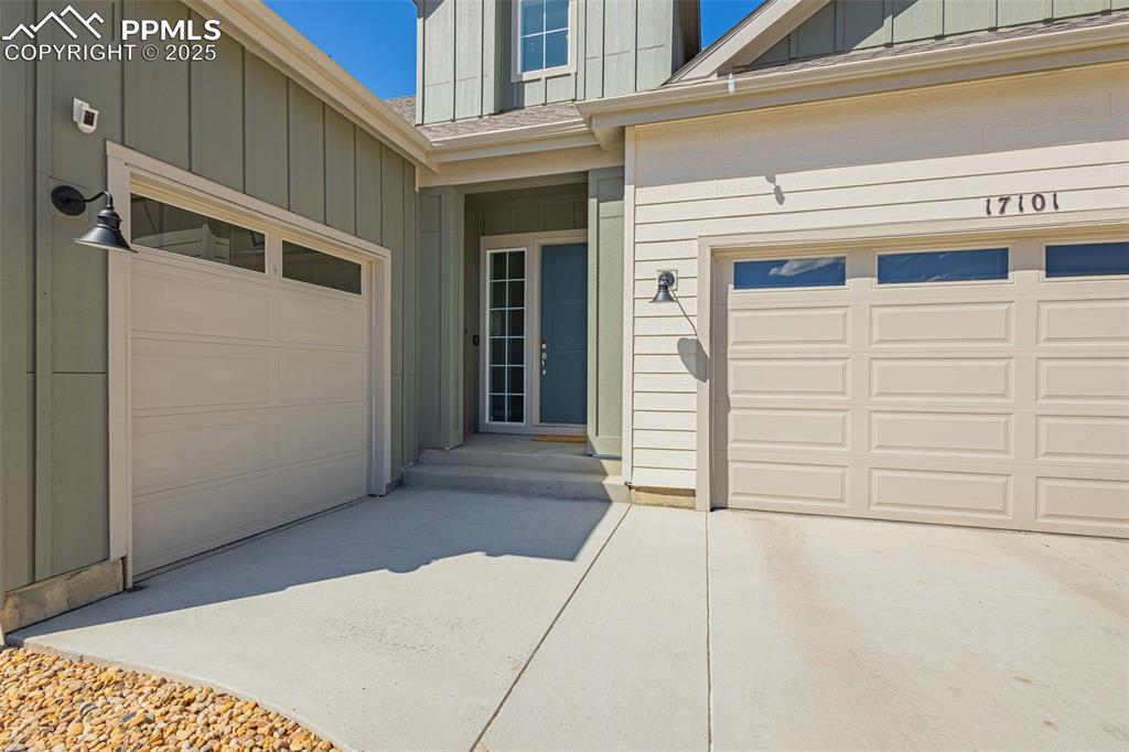 Image 3 of 47: Entrance to property with concrete driveway, board and batten siding, roof 