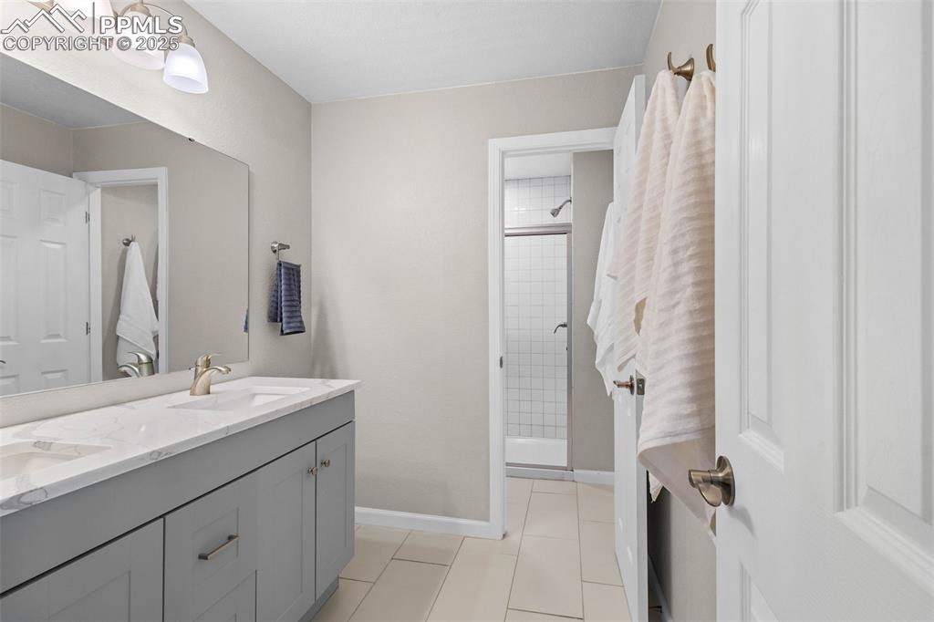 Image 34 of 47: Bathroom featuring double vanity, a stall shower, and tile patterned floors