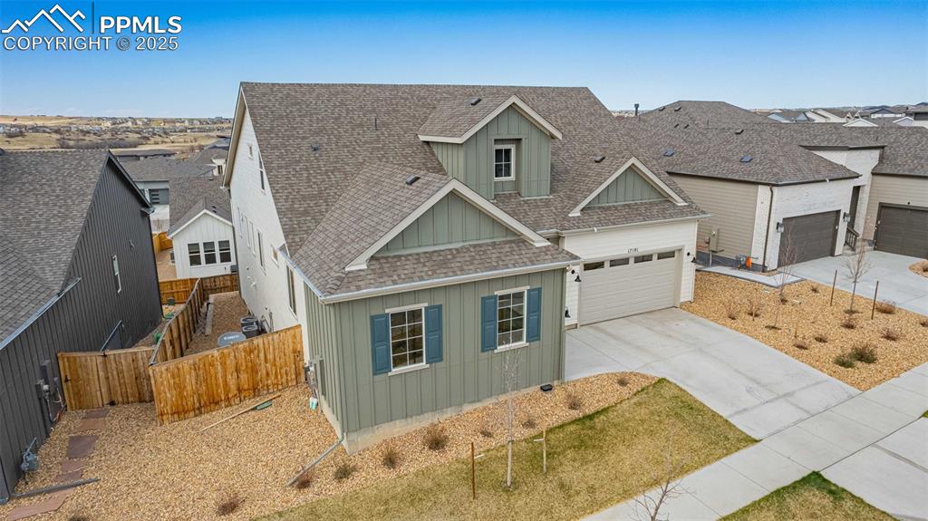 Image 37 of 47: View of front facade with a shingled roof, concrete driveway, board and bat