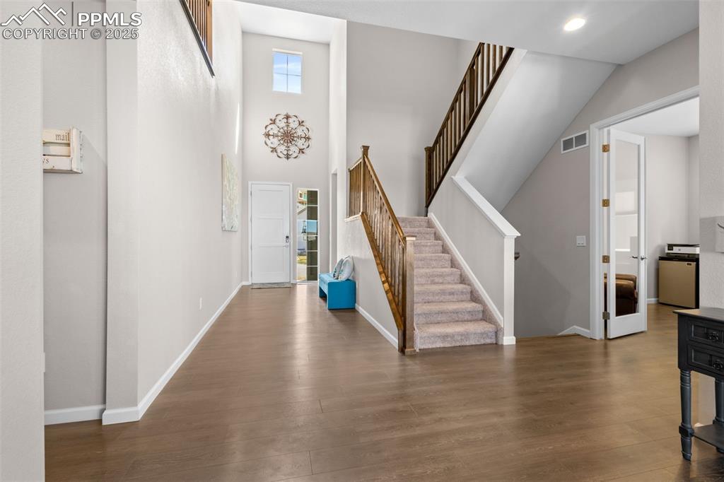 Image 4 of 47: Entrance foyer featuring wood finished floors, stairway, and a towering cei