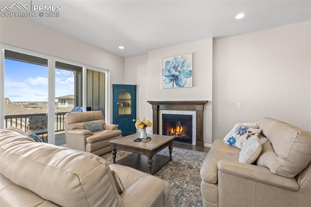 Image 5 of 47: Living area with wood finished floors, recessed lighting, and a tiled firep