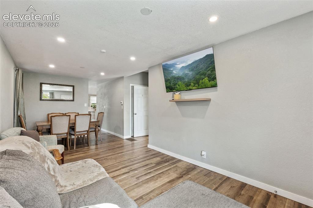 Image 11 of 50: Open-concept living area featuring wood-finish flooring, recessed lighting,