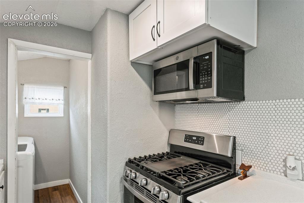 Image 15 of 50: Kitchen with stainless steel gas range, over-the-range microwave, white sha