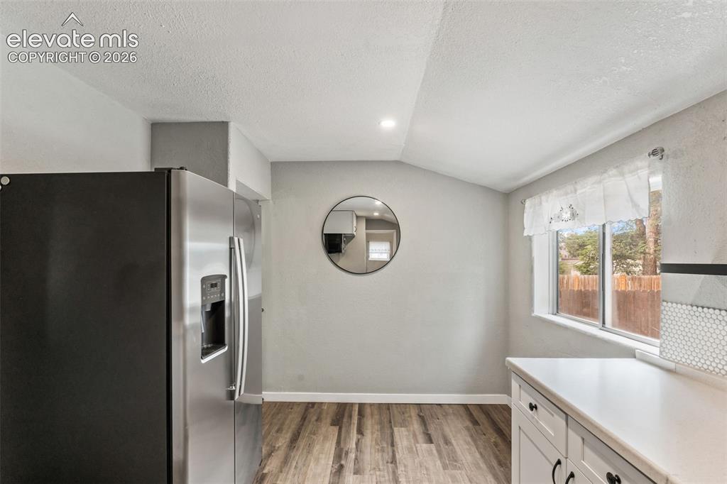 Image 16 of 50: Contemporary kitchen featuring wood-finish flooring, white cabinetry with d