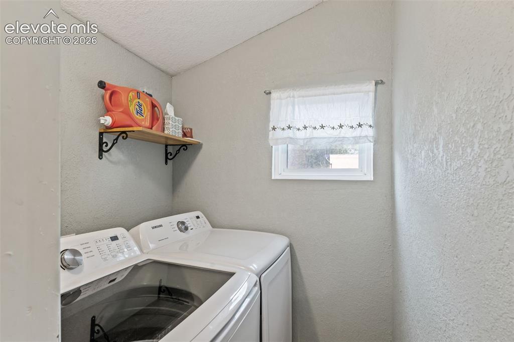 Image 19 of 50: Dedicated laundry area featuring a window, textured walls, and a built-in w
