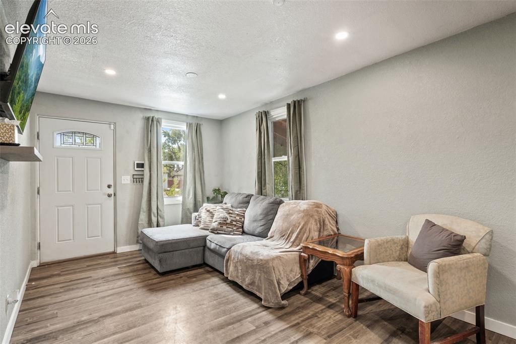 Image 2 of 50: Open living area featuring wood-finish flooring, recessed ceiling lighting,