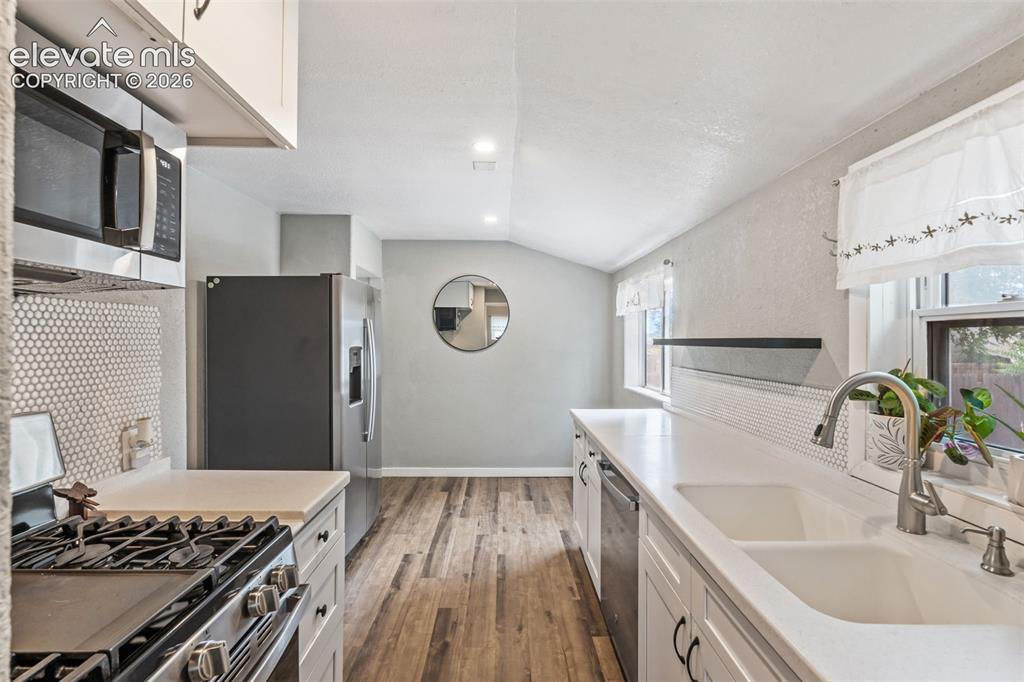 Image 20 of 50: Kitchen featuring white cabinetry, light countertops, and wood-finish floor