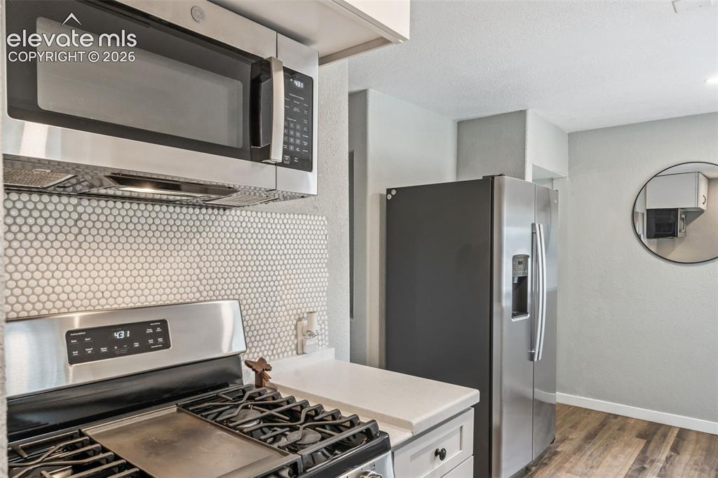 Image 21 of 50: Kitchen featuring stainless steel appliances, white penny tile backsplash,