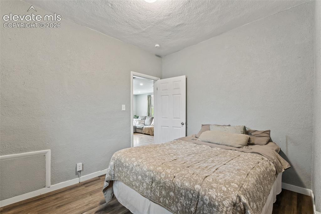 Image 24 of 50: Bedroom featuring wood-finish flooring, light gray textured walls, and a wh