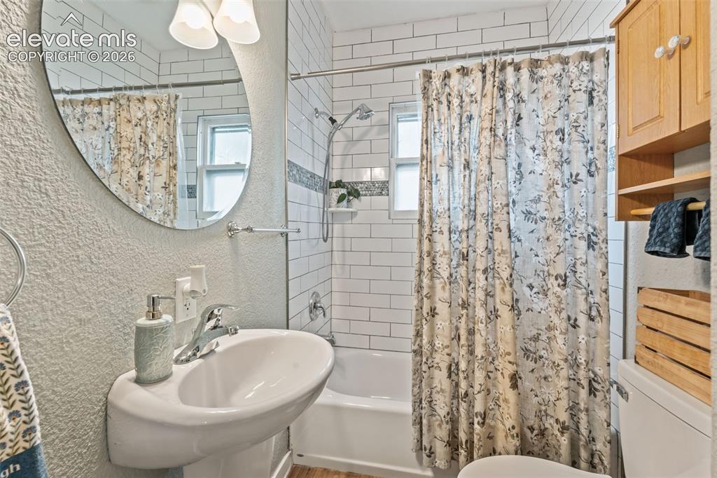 Image 25 of 50: Bathroom featuring a white subway tile shower surround with an accent tile