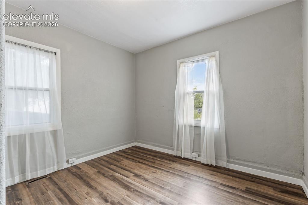 Image 26 of 50: Room featuring wood-finish flooring, light gray wall paint, and white trim