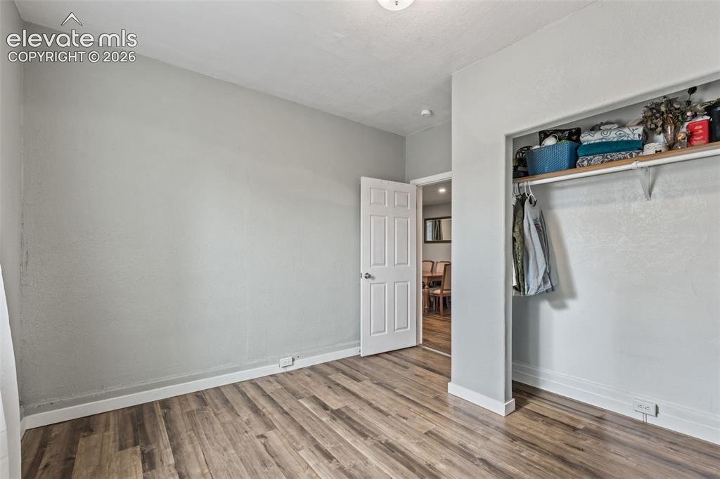 Image 28 of 50: Room featuring wood-finish flooring, a neutral wall color, white baseboards