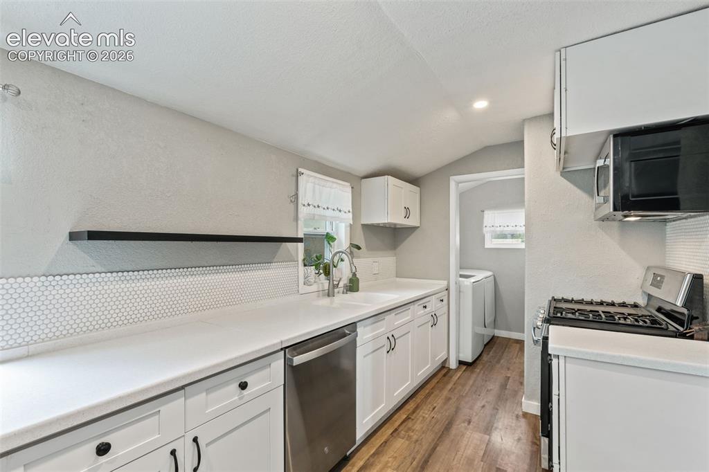 Image 3 of 50: Kitchen featuring white shaker cabinetry, white countertops, a white penny