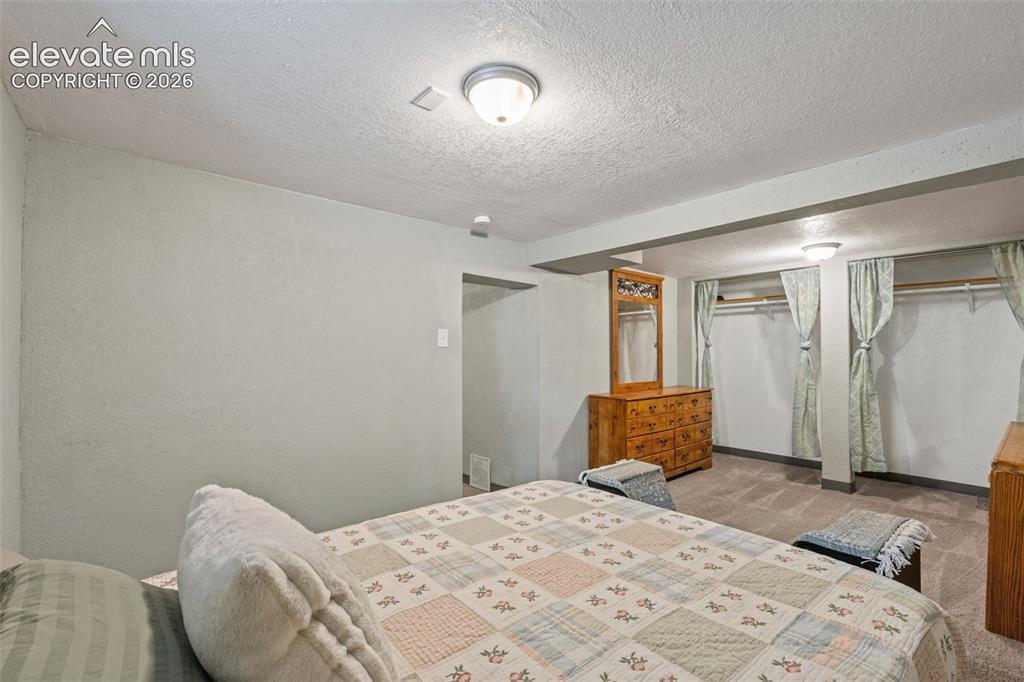 Image 35 of 50: Carpeted bedroom area featuring recessed open closets with curtain covering