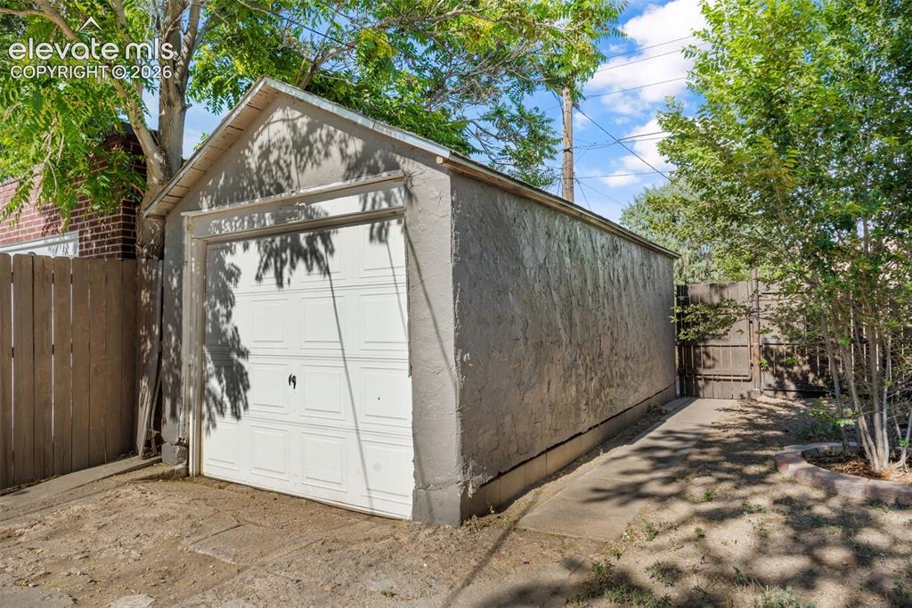 Image 42 of 50: Detached single-car garage featuring a white panel door and stucco exterior