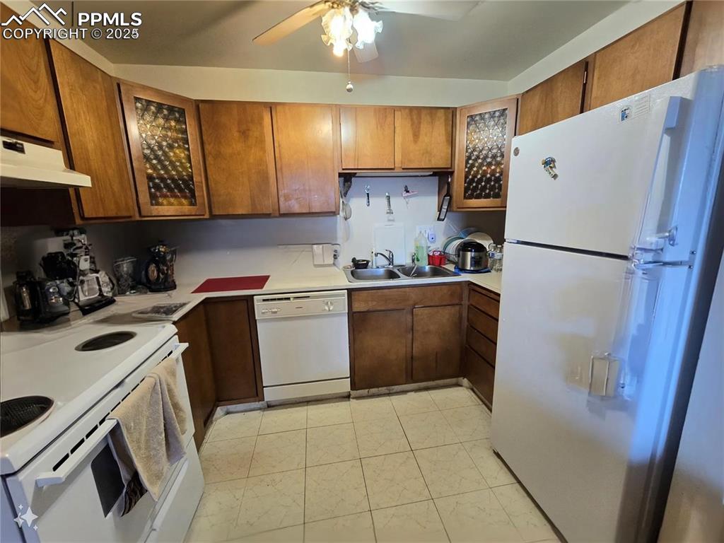 Image 10 of 18: Kitchen with white appliances, a sink, under cabinet range hood, ceiling fa