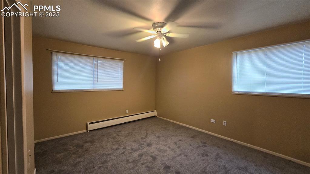 Image 3 of 18: Empty room featuring a baseboard radiator, dark colored carpet, healthy amo