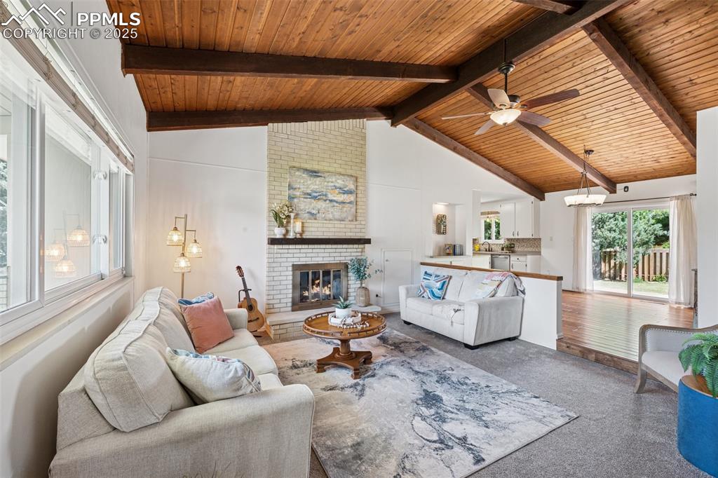 Image 15 of 34: Carpeted living room with a wood ceiling with exposed beams, a fireplace, a