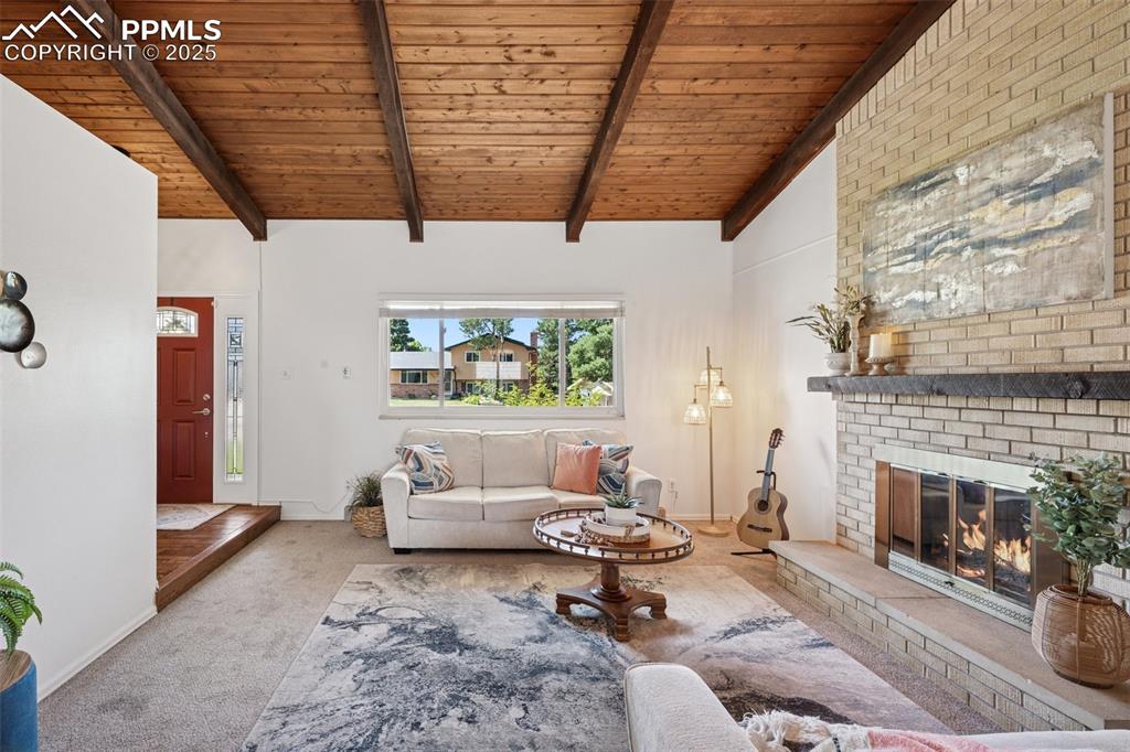 Image 16 of 34: Carpeted living room featuring a wooden ceiling with exposed beams, a brick
