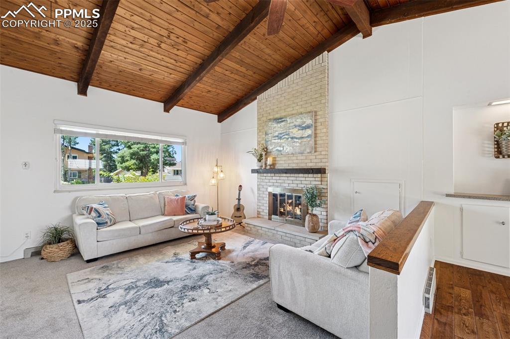 Image 18 of 34: Living room with a wooden ceiling with exposed beams, a brick fireplace, an