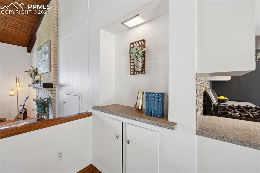 Image 20 of 34: Detailed view of white cabinets, a large fireplace, and stove