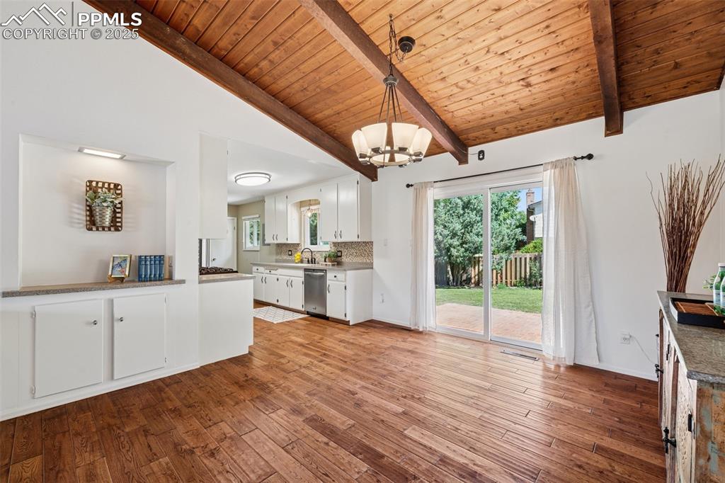 Image 21 of 34: Kitchen and dining area featuring a chandelier, white cabinets, hardwood /