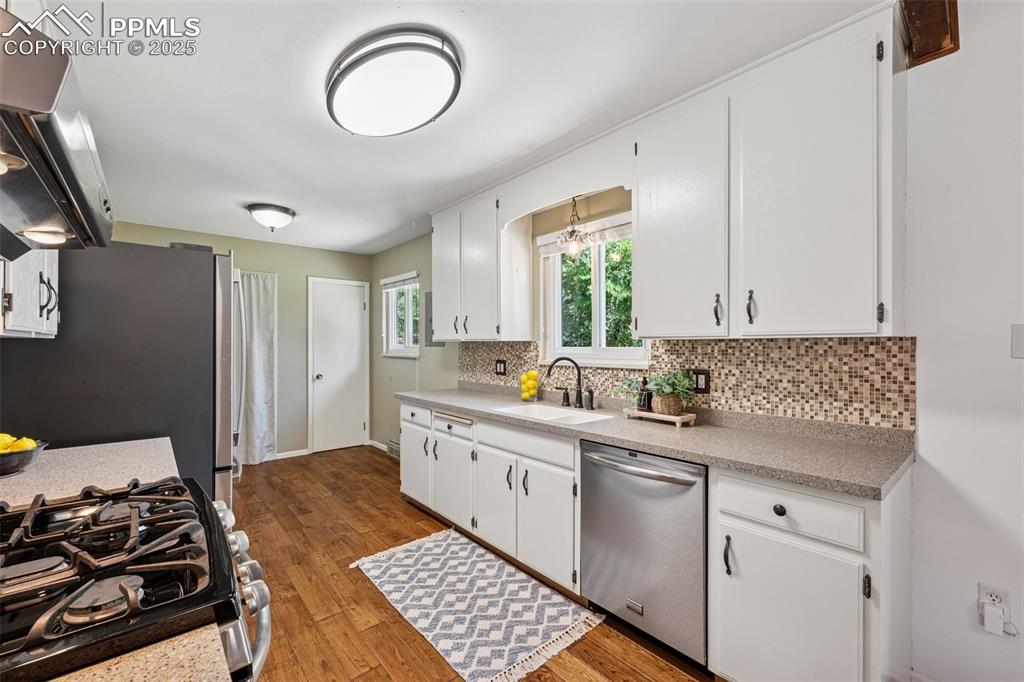 Image 23 of 34: Kitchen with backsplash, wood finished floors, appliances with stainless st