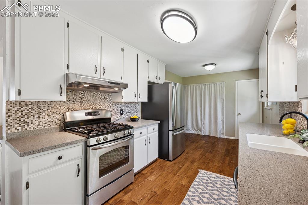 Image 24 of 34: Kitchen featuring tasteful backsplash, stainless steel appliances, under ca