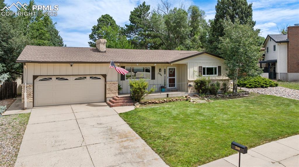 Image 3 of 34: Ranch-style house with board and batten siding, an attached garage, drivewa