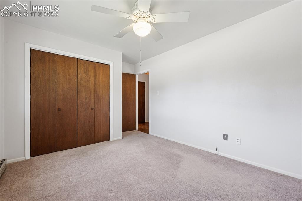 Image 34 of 34: Bedroom #3 with a closet, light colored carpet, and a ceiling fan