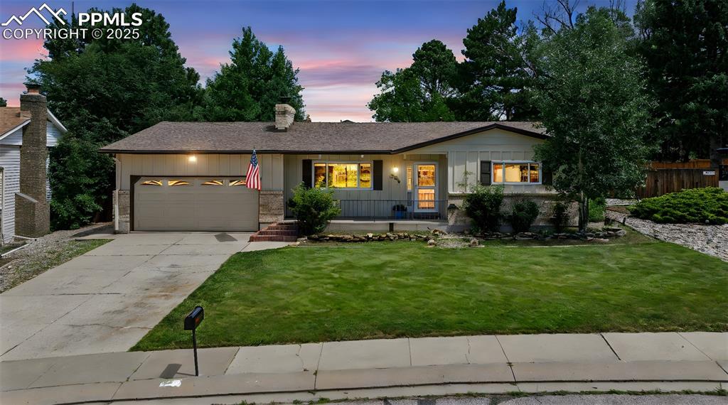 Image 4 of 34: Ranch-style home with a garage, driveway, board and batten siding, a chimne