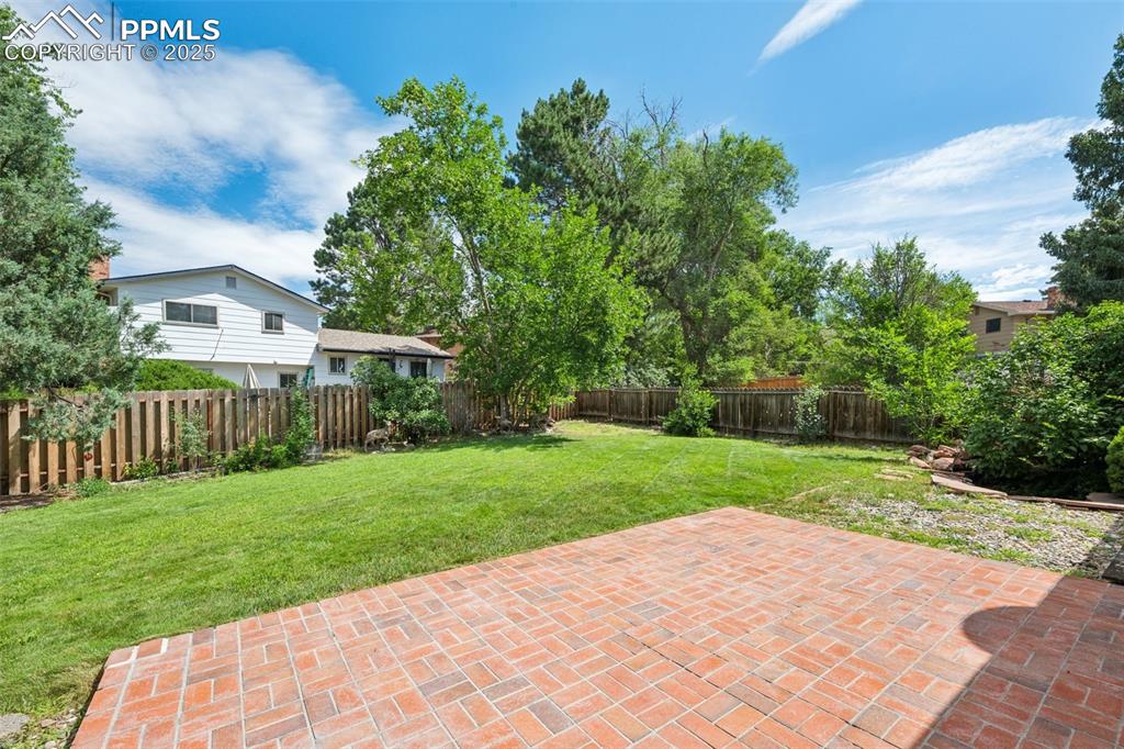 Image 8 of 34: Fenced backyard with a patio