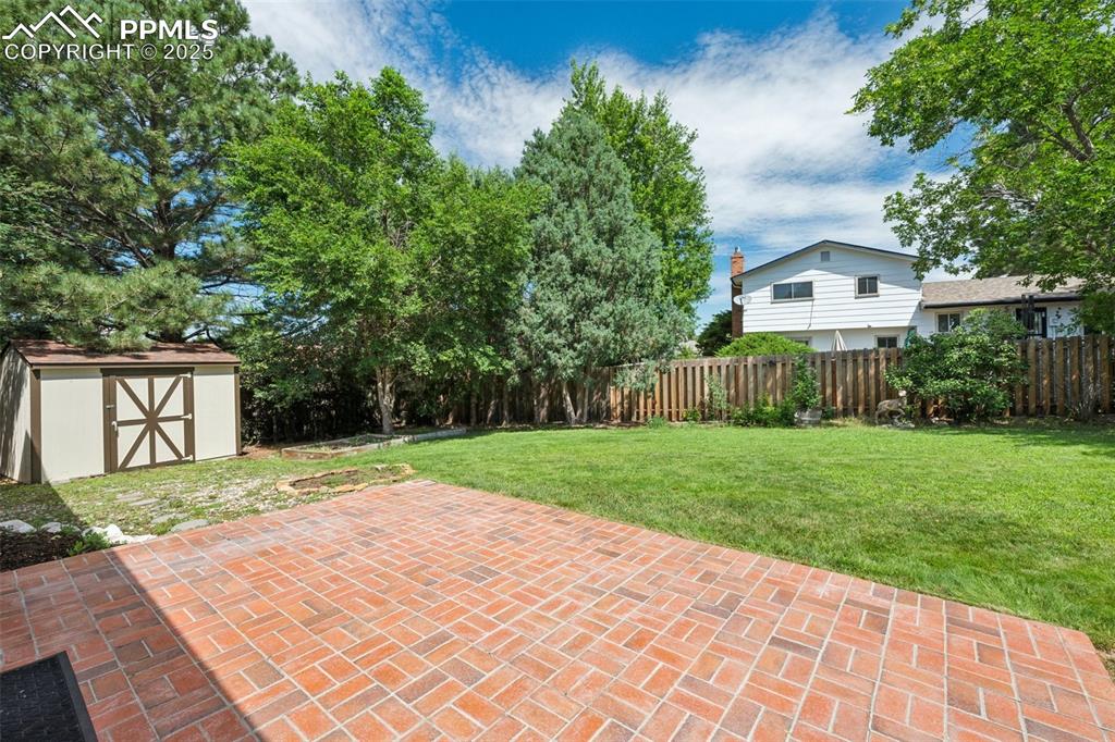 Image 9 of 34: Fenced backyard with a storage unit and a patio area