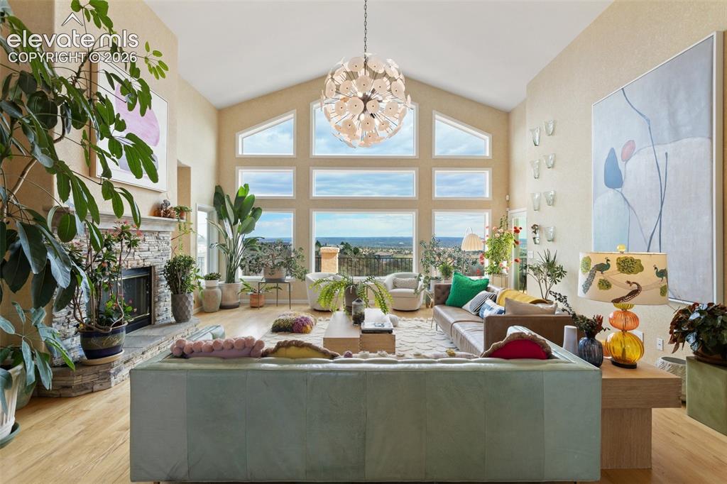 Image 10 of 50: Vaulted living space featuring a stacked stone fireplace, wood-finish floor
