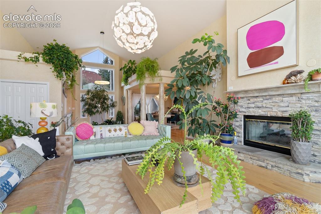 Image 11 of 50: Living area featuring vaulted ceilings, a stacked stone fireplace, hardwood