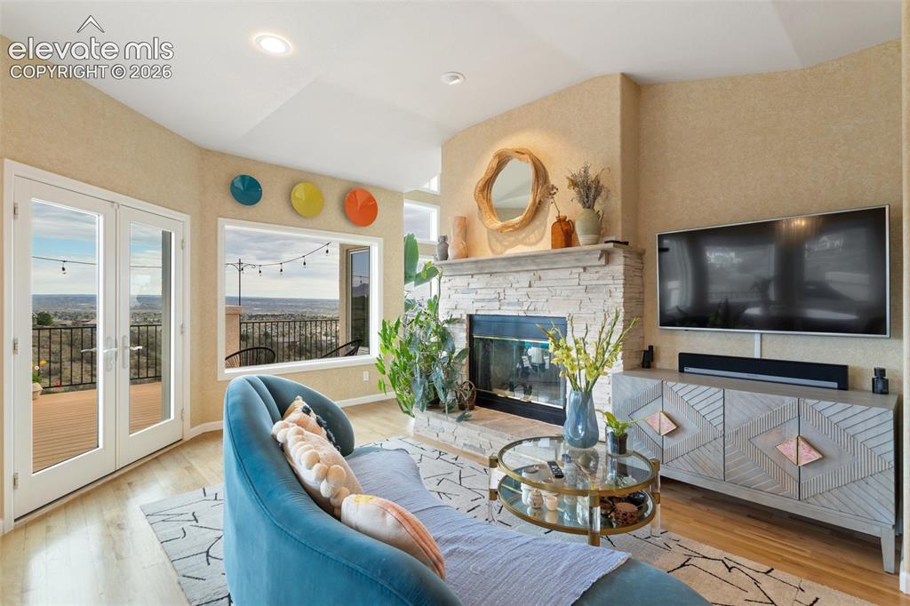 Image 15 of 50: Spacious living area featuring a stone-clad fireplace, light wood-finish fl