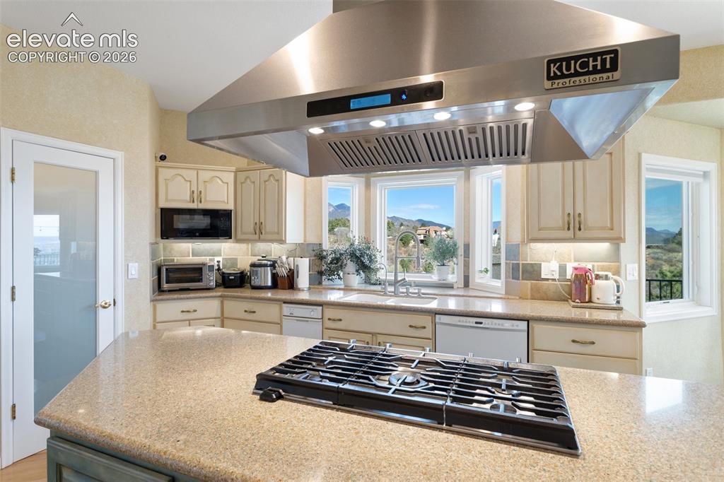 Image 17 of 50: Kitchen featuring a large stainless steel professional range hood, central