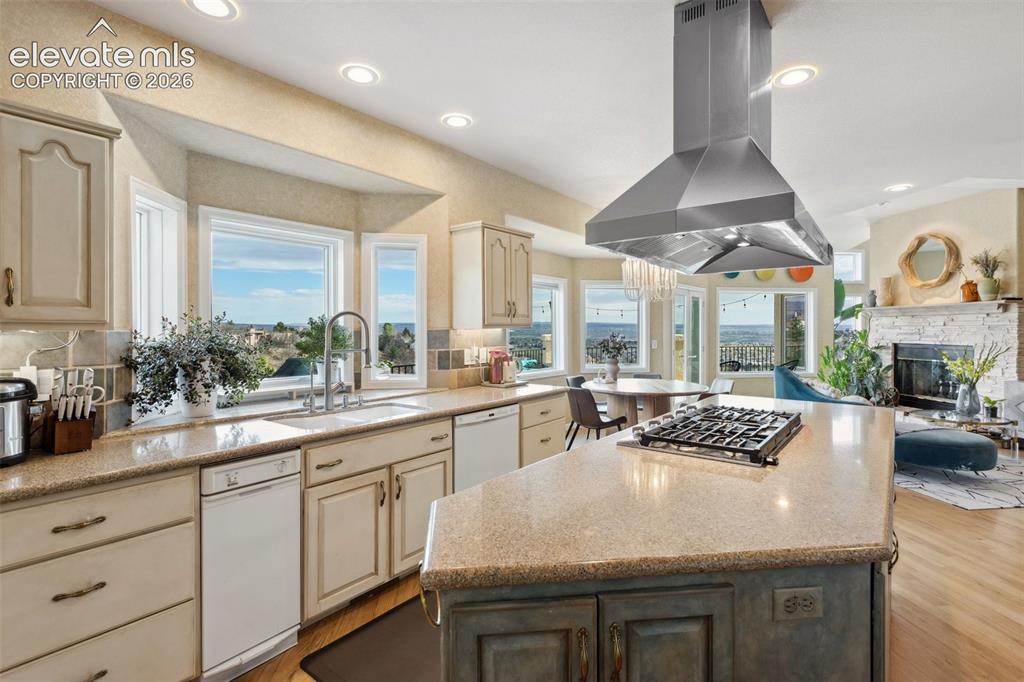 Image 19 of 50: Kitchen featuring an island with a built-in gas cooktop, stainless steel ra