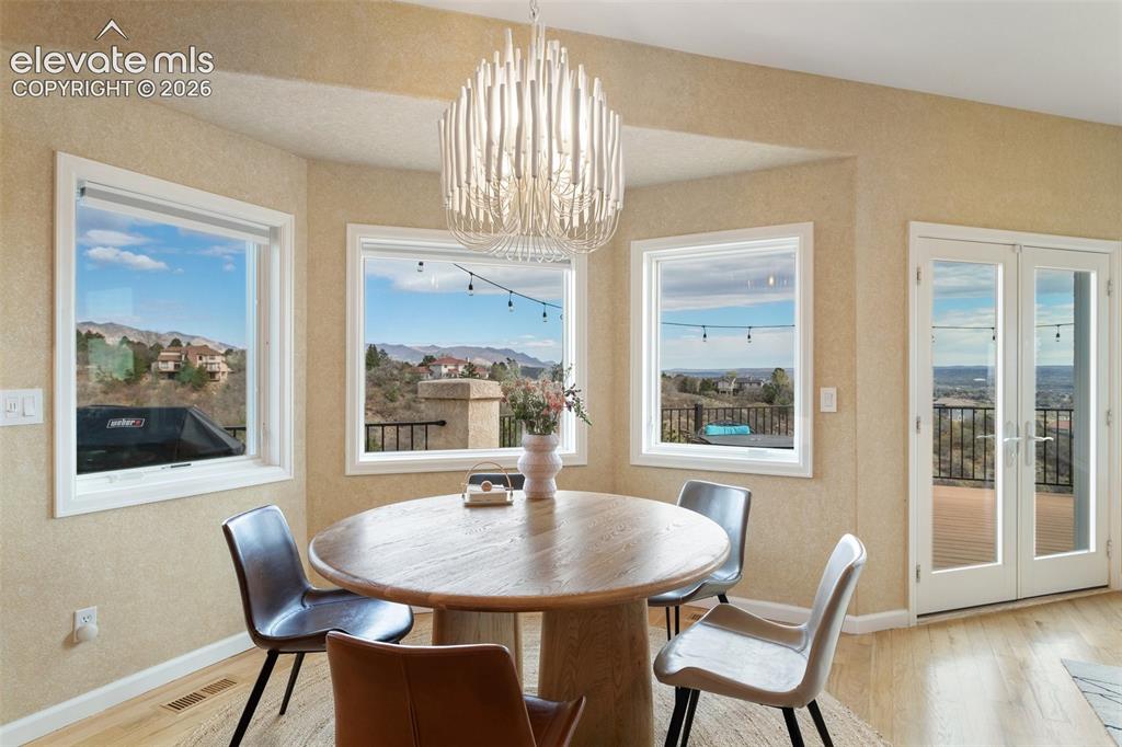 Image 24 of 50: Dining area featuring a contemporary chandelier, multiple windows with moun