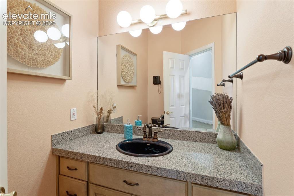 Image 26 of 50: Bathroom vanity featuring a speckled countertop, a black oval sink, and a b