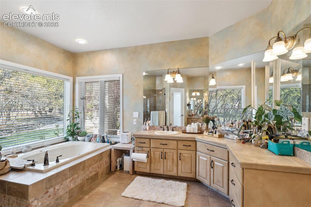 Image 29 of 50: Alcove soaking tub with tile surround, dual vanities with integrated sinks,